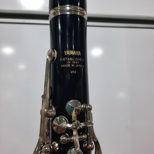 Clarinet with silver keys and black body on a reflective surface