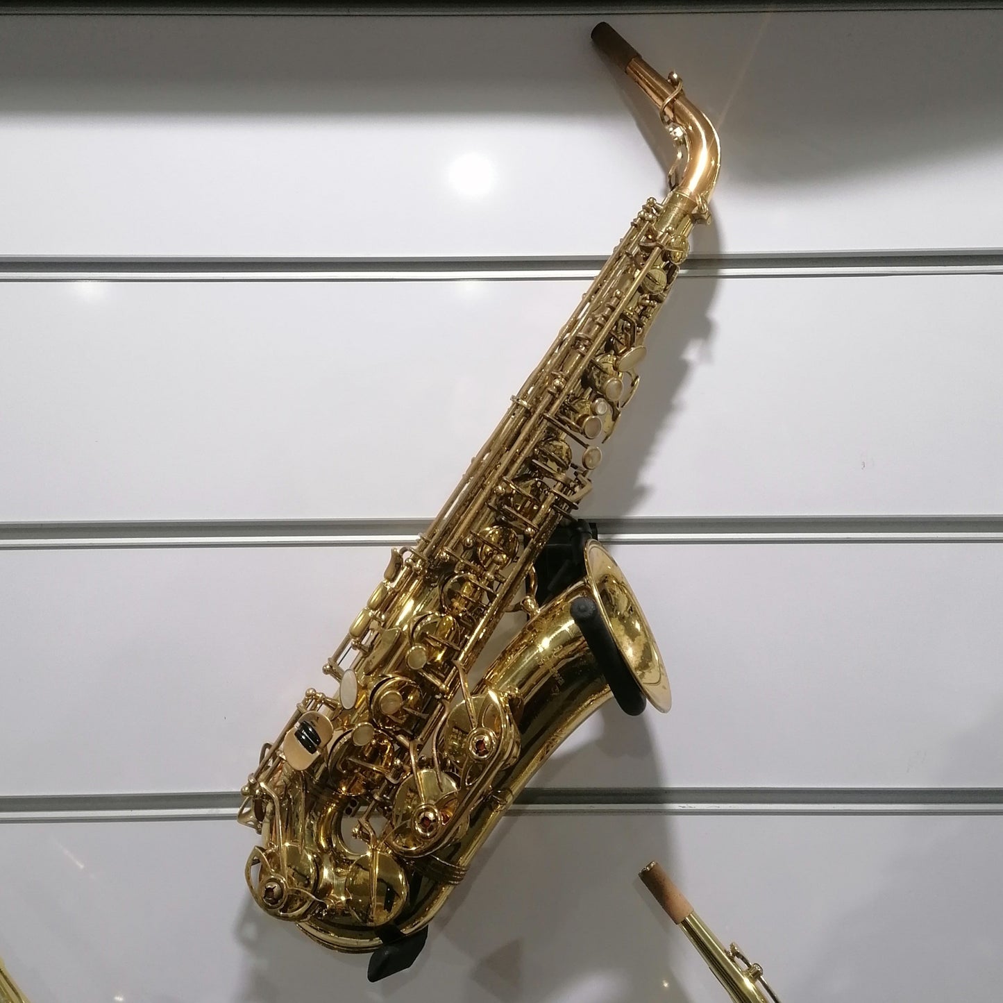 Gold saxophone on a white wall with a label below