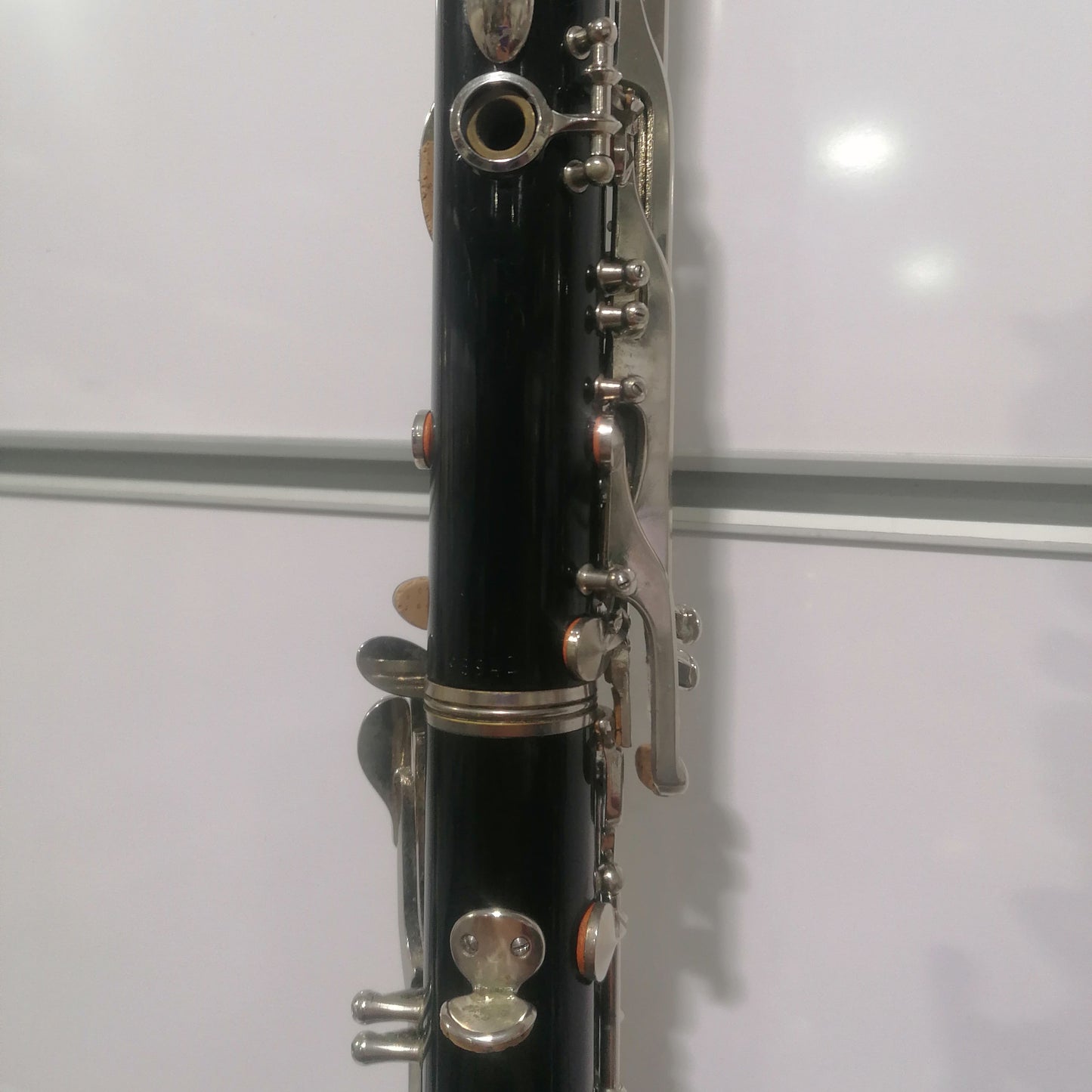 Close-up of a black clarinet with silver keys against a white background