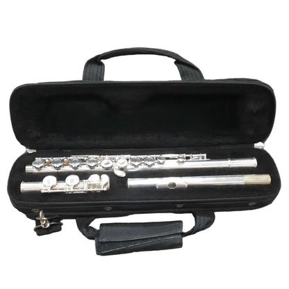 A silver flute resting inside an open black hard case on a gray carpeted floor.