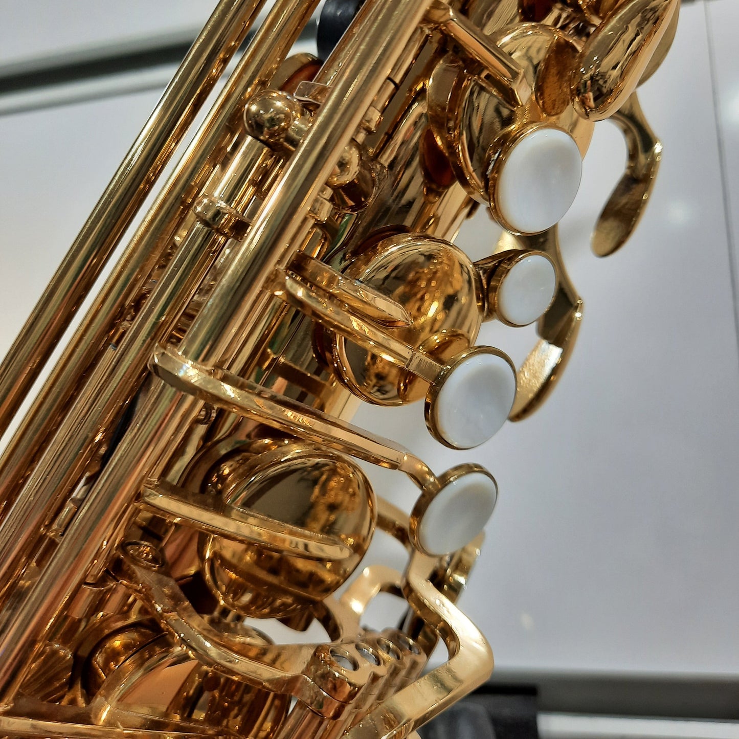 Close-up of a gold saxophone with white keys on a blurred background