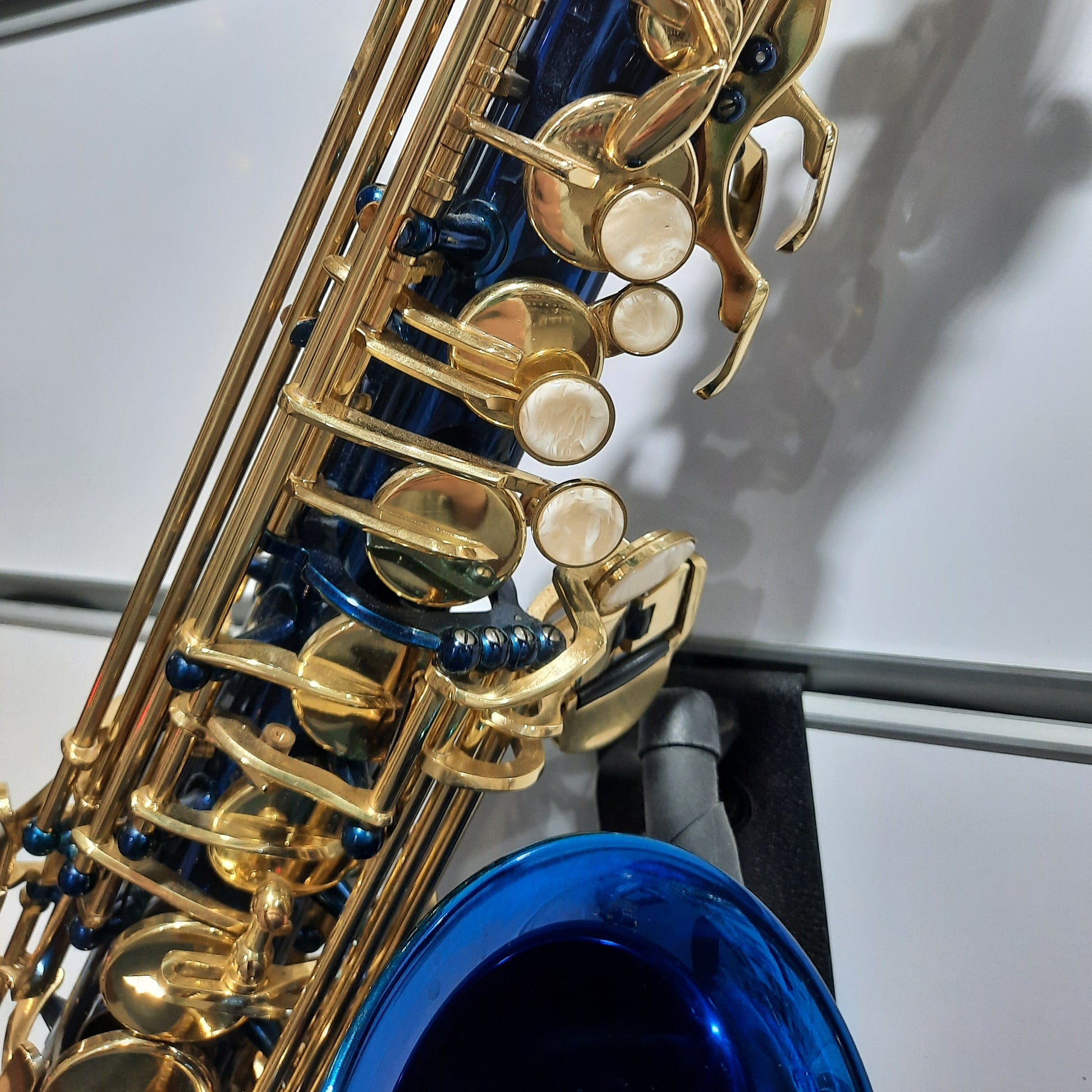 Close-up of a gold and blue saxophone on a stand