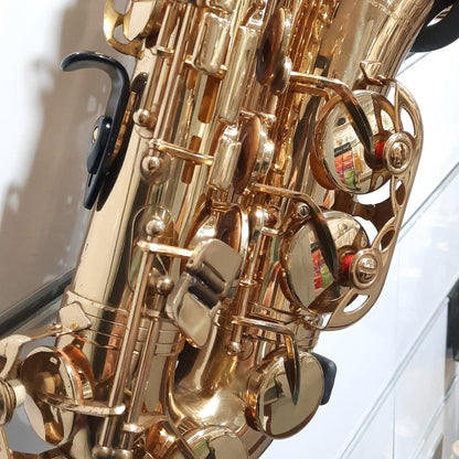 Gold saxophone on a stand with a white background