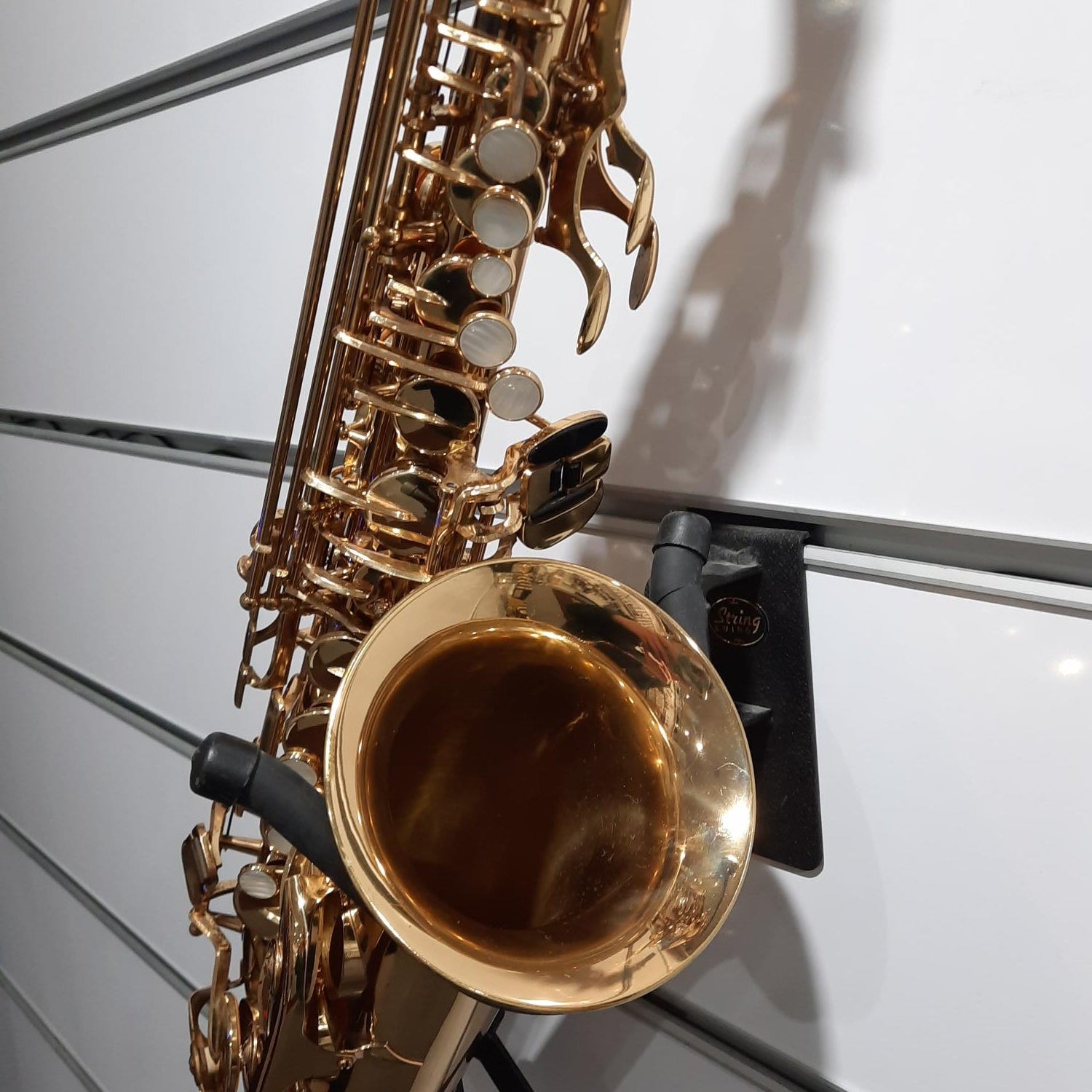 Gold saxophone on a stand against a white background