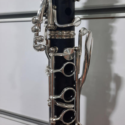 Close-up of a clarinet with silver keys on a reflective surface