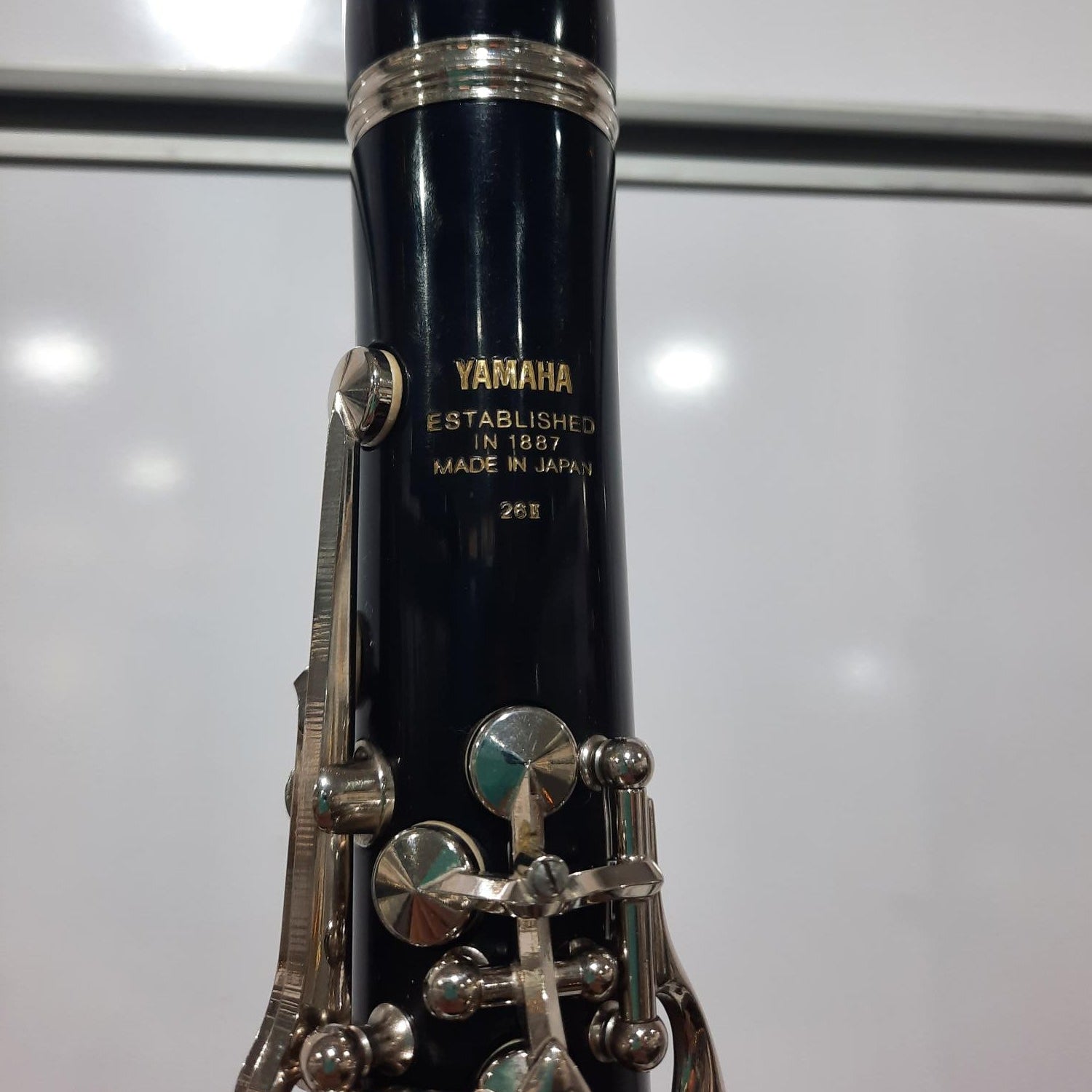 Clarinet with silver keys and black body on a reflective surface
