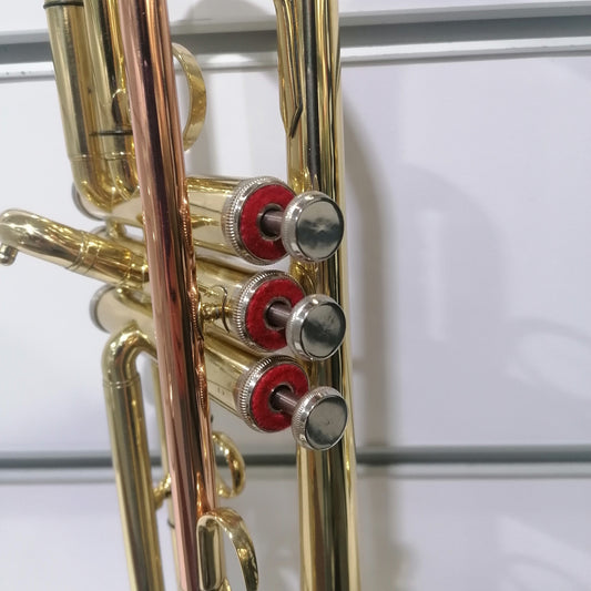 Close-up of a brass instrument with red and silver components on a white background