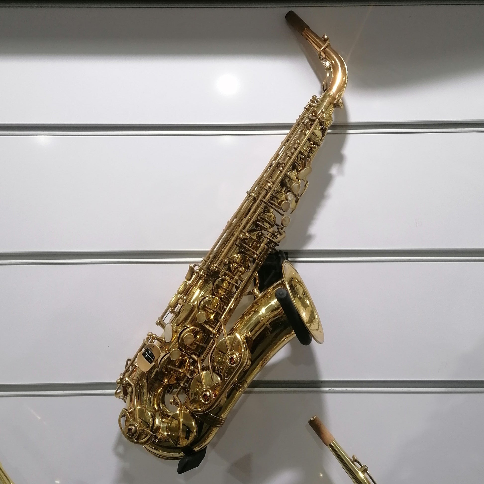 Gold saxophone on a white wall with a label below