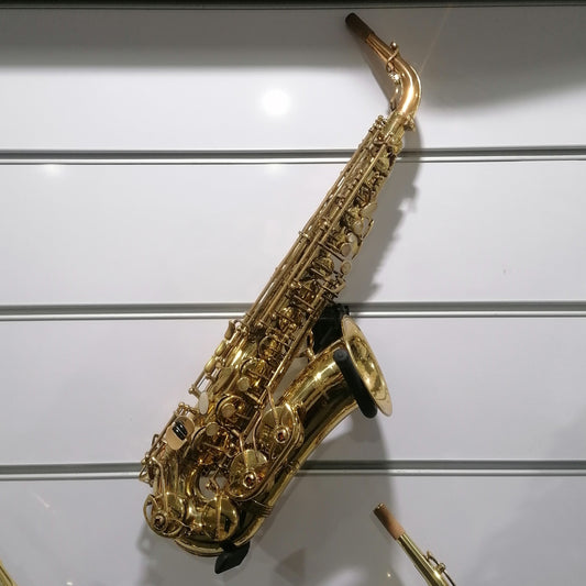 Gold saxophone on a white wall with a label below