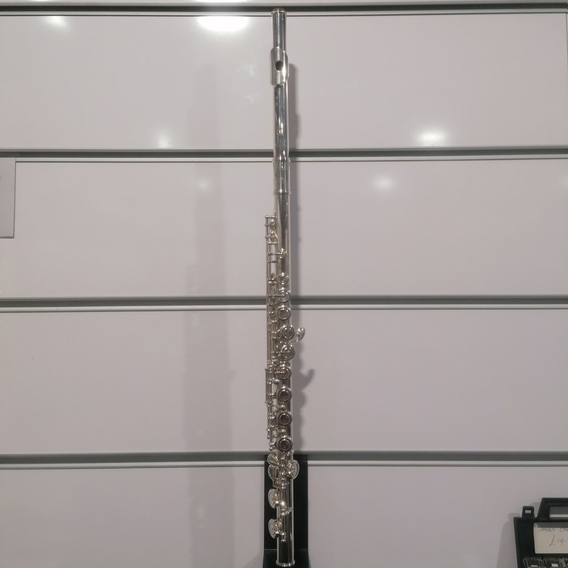 Silver flute against a light gray background