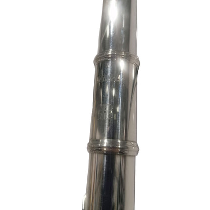 Close-up of a silver flute with 'Yamaha' branding on a white background