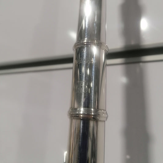 Close-up of a silver flute with 'Yamaha' branding on a white background