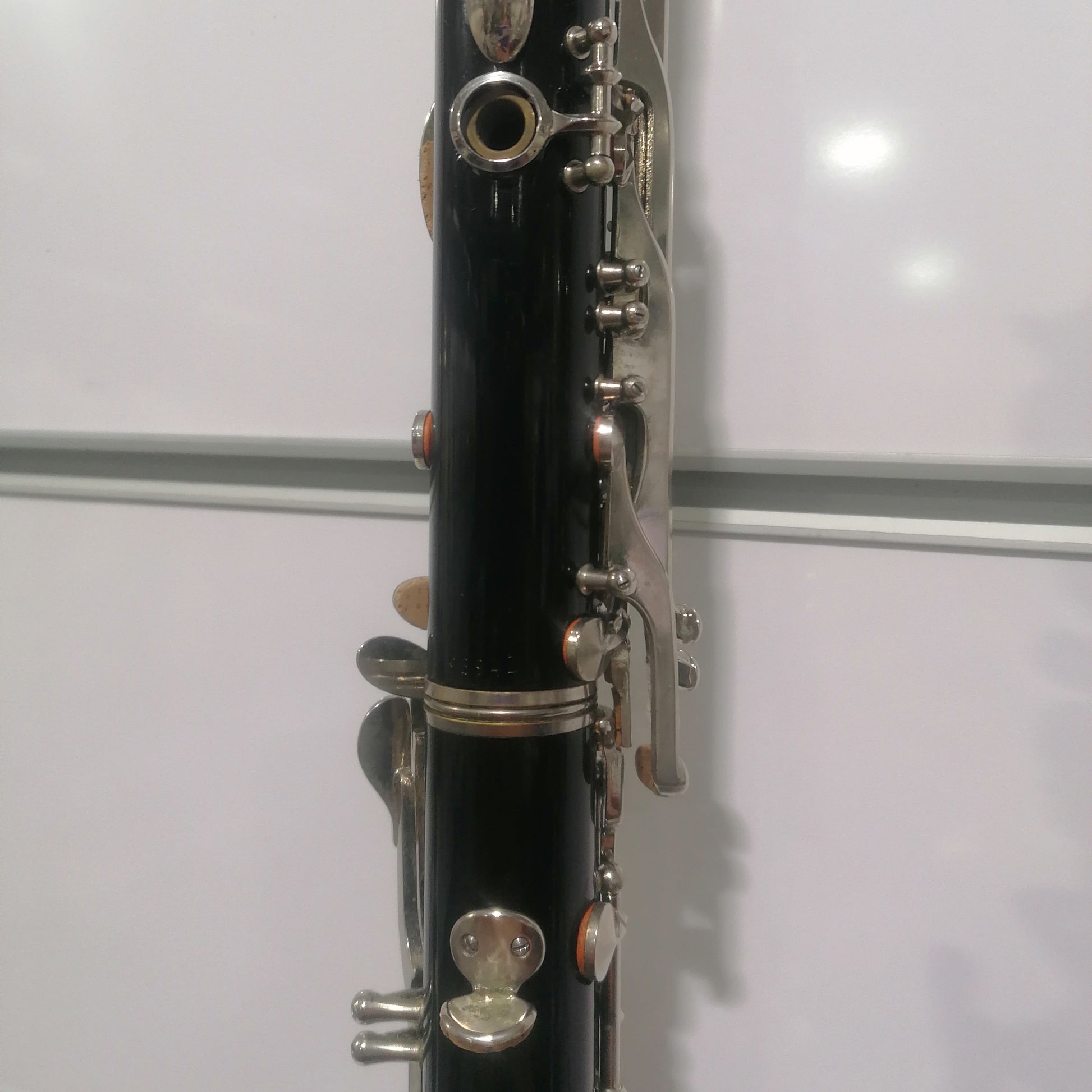 Close-up of a black clarinet with silver keys against a white background